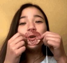 a young girl is eating a donut with a straw in her mouth .