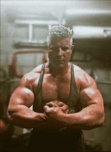 a man with his arms crossed is wearing a black tank top and a watch