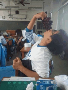 a person eating grapes in a classroom with a carton of nissin milk