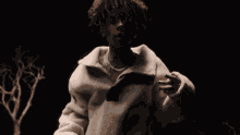 a young man with curly hair is wearing a white jacket and a necklace .