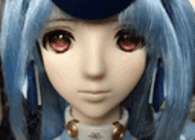 a doll with blue hair and red eyes is wearing a blue hat and headphones .