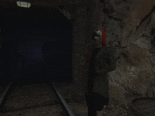 a person wearing a red hat and a green jacket stands in a dark tunnel