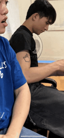 a man with a tattoo on his arm is wearing a blue shirt that says us