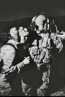 a black and white photo of two soldiers talking to each other