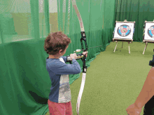 a young boy is holding a bow and arrow in front of a target that says ' pedro lee ' on it