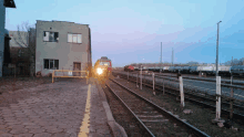 a train is pulling into a train yard with a yellow railing