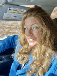 a woman is sitting in a car with a sticker on the visor that says warning