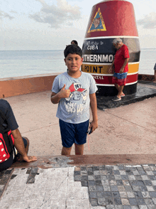 a boy stands in front of a buoy that says southernmost point