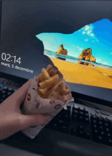 a person holding a bag of french fries in front of a computer screen that says 2:14