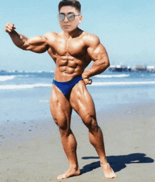 a very muscular man wearing sunglasses and a blue bikini is standing on a beach