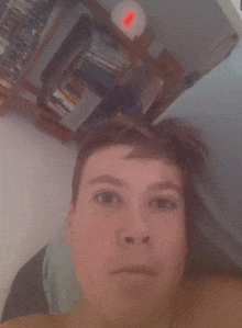 a young man taking a selfie in front of a bookshelf with books on it