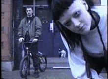 a man is riding a bike next to a woman who is looking at the camera .