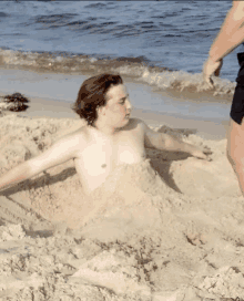 a young boy is buried in the sand on the beach