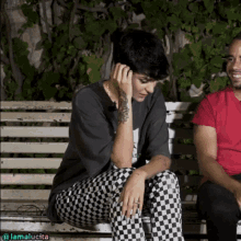 a woman sits on a bench next to a man in a red shirt with the name lamalucita on the bottom right