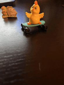 a toy chicken is sitting on a skateboard