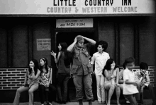 a group of people are sitting outside of a little country inn