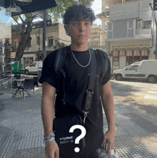 a young man wearing a black shirt and a backpack has a question mark on his shoulder