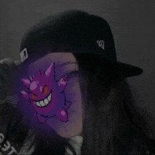 a girl wearing a black hat with a purple monster behind her face .