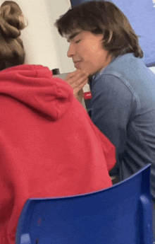 a girl in a red hoodie is sitting next to a boy in a blue shirt