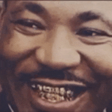 a close up of a man 's face with a beard and gold teeth smiling .