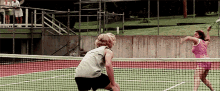 a man and a woman are playing tennis on a court with a sign in the background that says ' a & a '