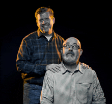 two men are posing for a picture and one has his arm around the other 's shoulders