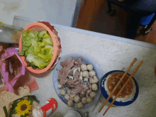 a plate of meatballs sits on a counter next to a basket of lettuce and chopsticks