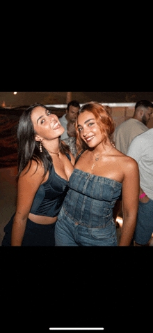 two women are posing for a picture together and one is wearing a denim top