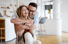 a man is carrying a woman in a hammock and they are laughing together