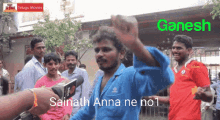 a man in a blue shirt is being interviewed by a person with a microphone in front of a sign that says ganesh