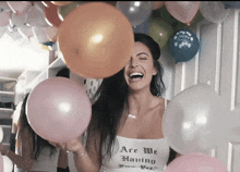 a woman wearing a shirt that says ' are we having fun yet ' holds balloons