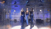 three women are dancing in a dark room with purple lights