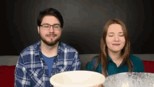 a man and a woman are sitting next to each other with their eyes closed and a bowl of water in front of them .