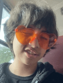 a young boy wearing heart shaped sunglasses is making a face .