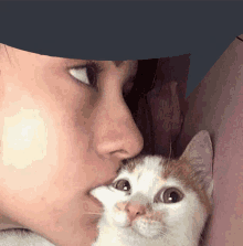 a woman is holding a cat in her arms and the cat is licking the woman 's nose