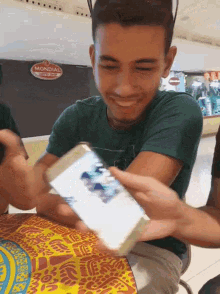 a man in a green shirt is smiling while holding a card in front of a sign that says mundial