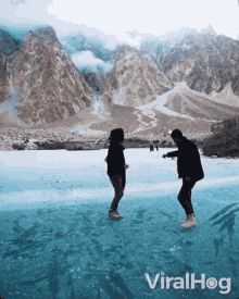 two people standing on a frozen lake with mountains in the background and the words viralhog on the bottom right