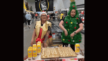 a woman in a christmas tree costume is standing next to a woman in a santa hat in a store .