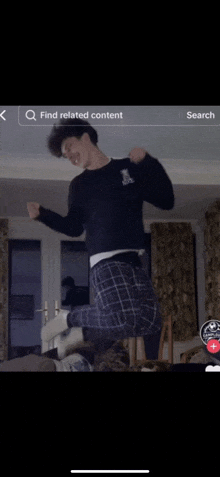 a young man is jumping in the air in a living room .