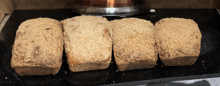 four loaves of bread are sitting on a black counter top