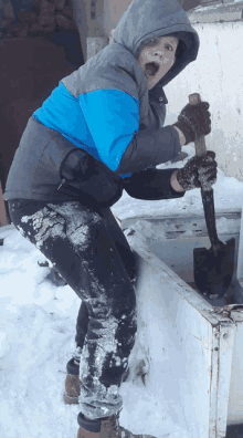 a boy in a blue and gray jacket is holding a shovel