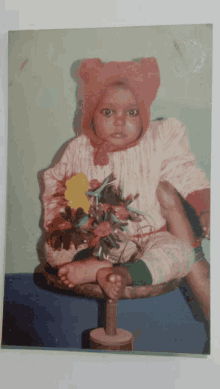 a baby wearing a red bear hat is sitting on a stool