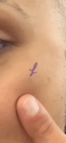 a close up of a person 's face with a purple butterfly tattoo on it .