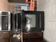 a kitchen with a black refrigerator and a stainless steel microwave