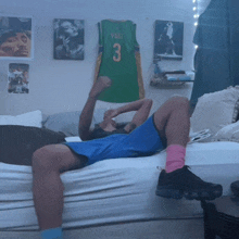 a man laying on a bed with a green nike jersey on the wall