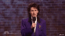 a woman in a purple suit is standing in front of a microphone .