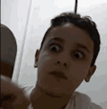 a young boy is making a funny face while looking at the camera in a bathroom .