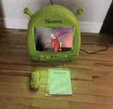 a shrek television with a remote control and a book