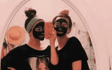 two girls are taking a selfie with their face masks on .