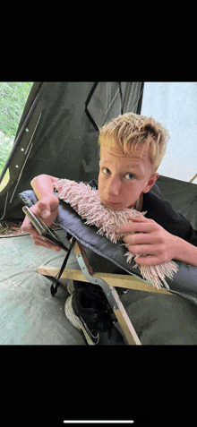 a young boy is sitting in a chair holding a phone in his hand